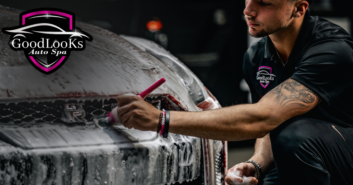 Athlete wipes a white vehicle with a cloth beside a GoodLooks Auto Detailing logo.