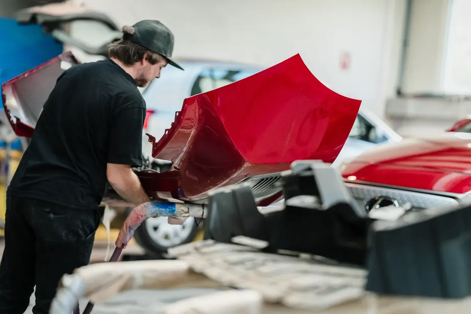 Person in a Cap Works on a Red Car in a Garage — Kingston Panel & Paint in Huntingfield, TAS