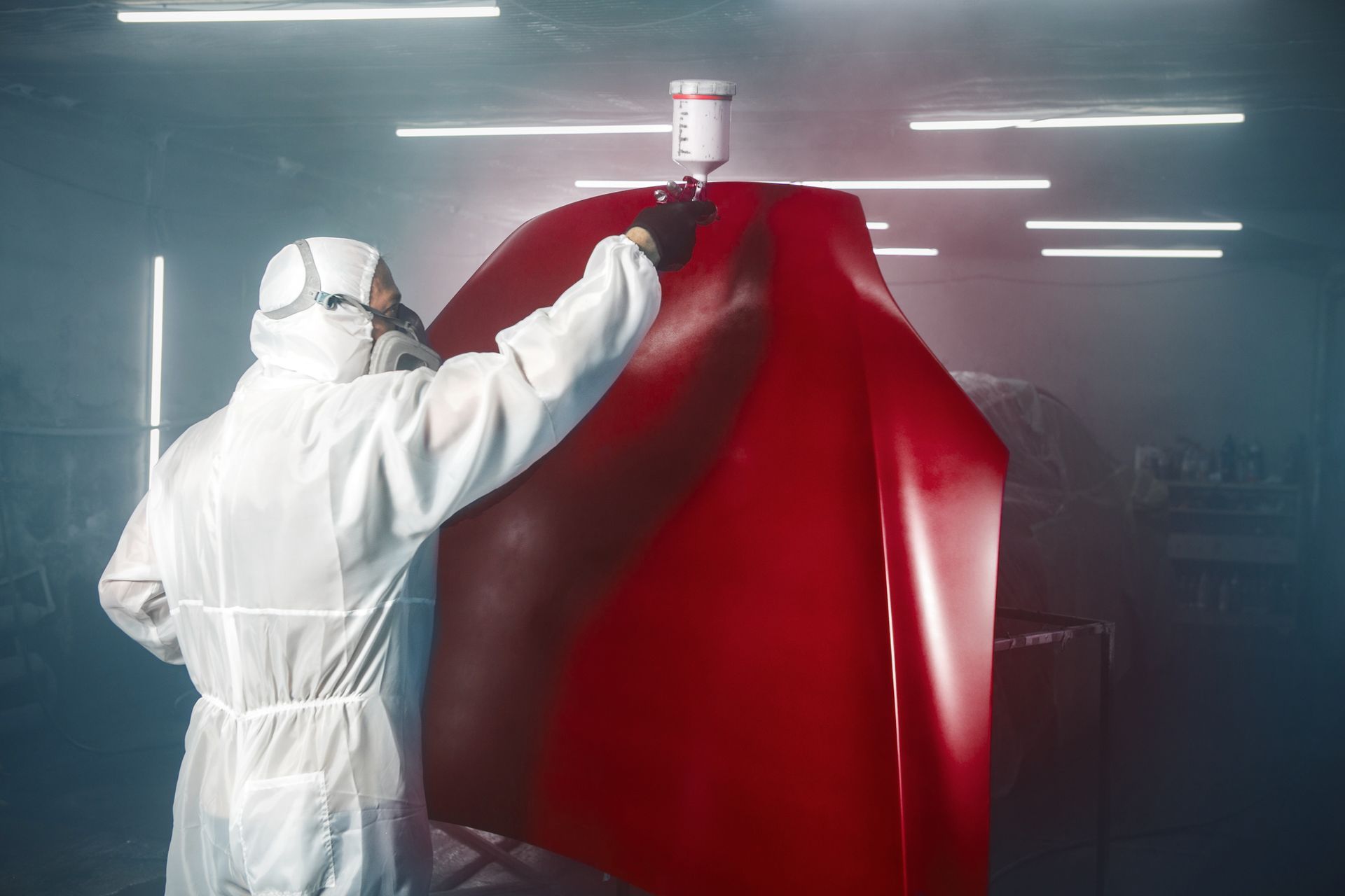Worker in White Protective Suit Spray-Painting a Large  Object in a Industrial Workshop — Kingston Panel & Paint in Huntingfield, TAS