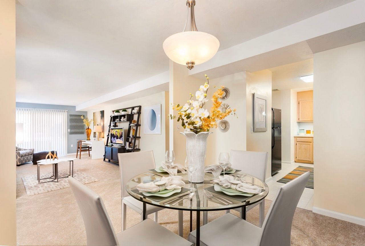 Open-concept dining area with glass table and living space in a modern apartment.