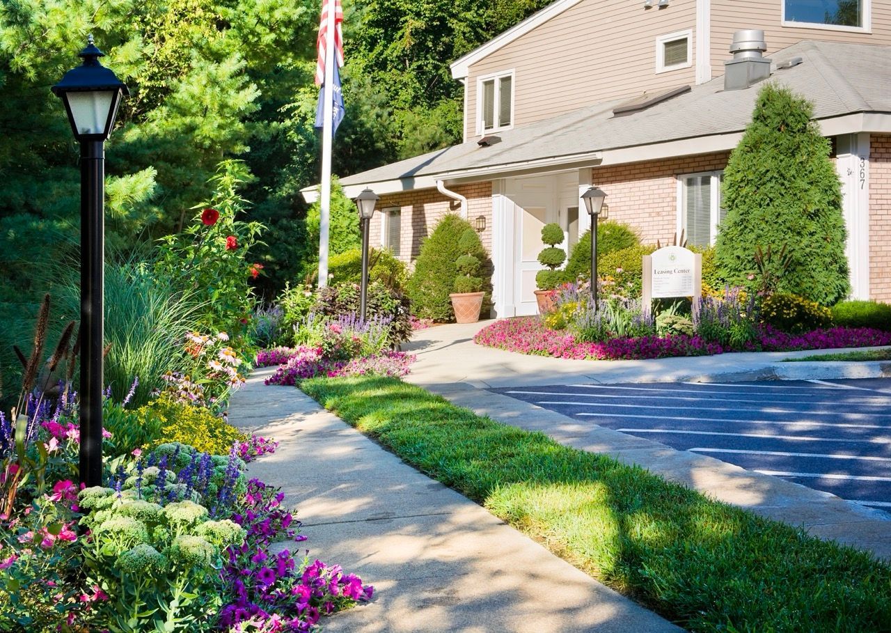 Exterior of a multifamily property with a landscaped walkway and lamps.