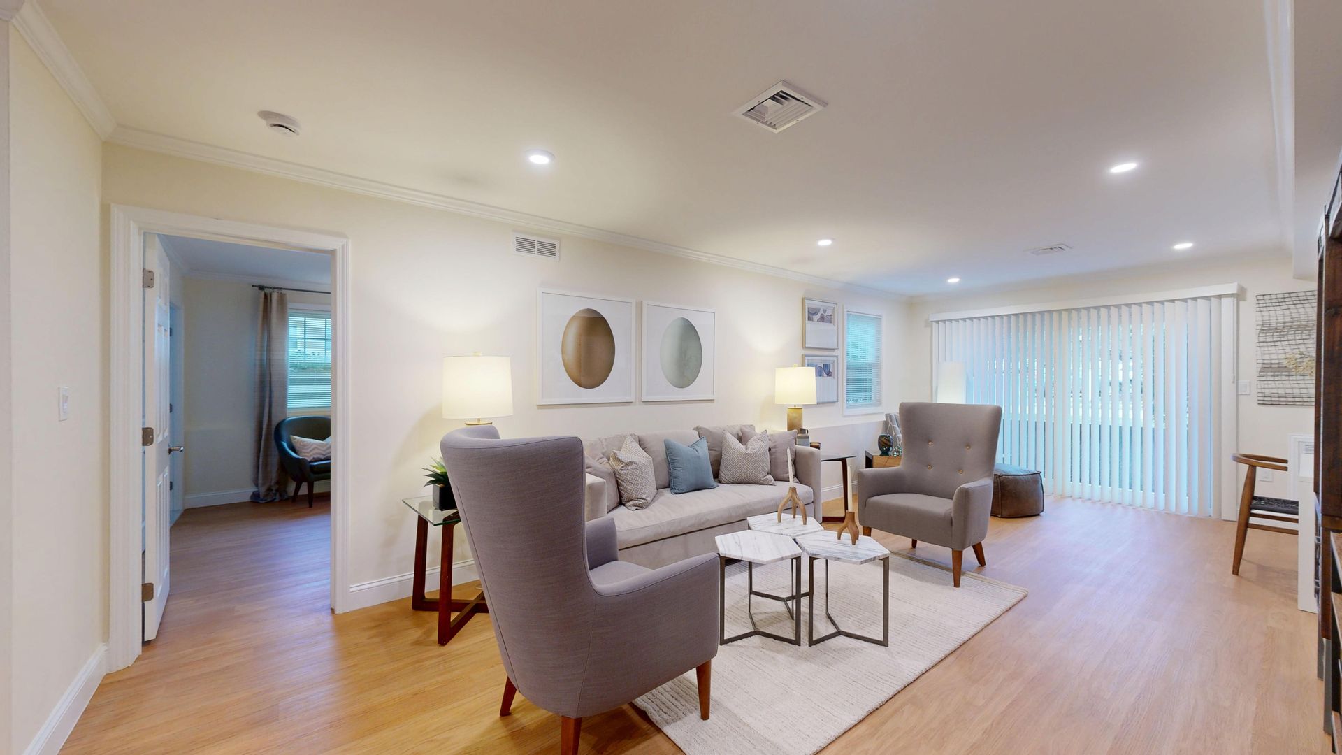 Bright modern living room with gray chairs, sofa, coffee table, and wood floors