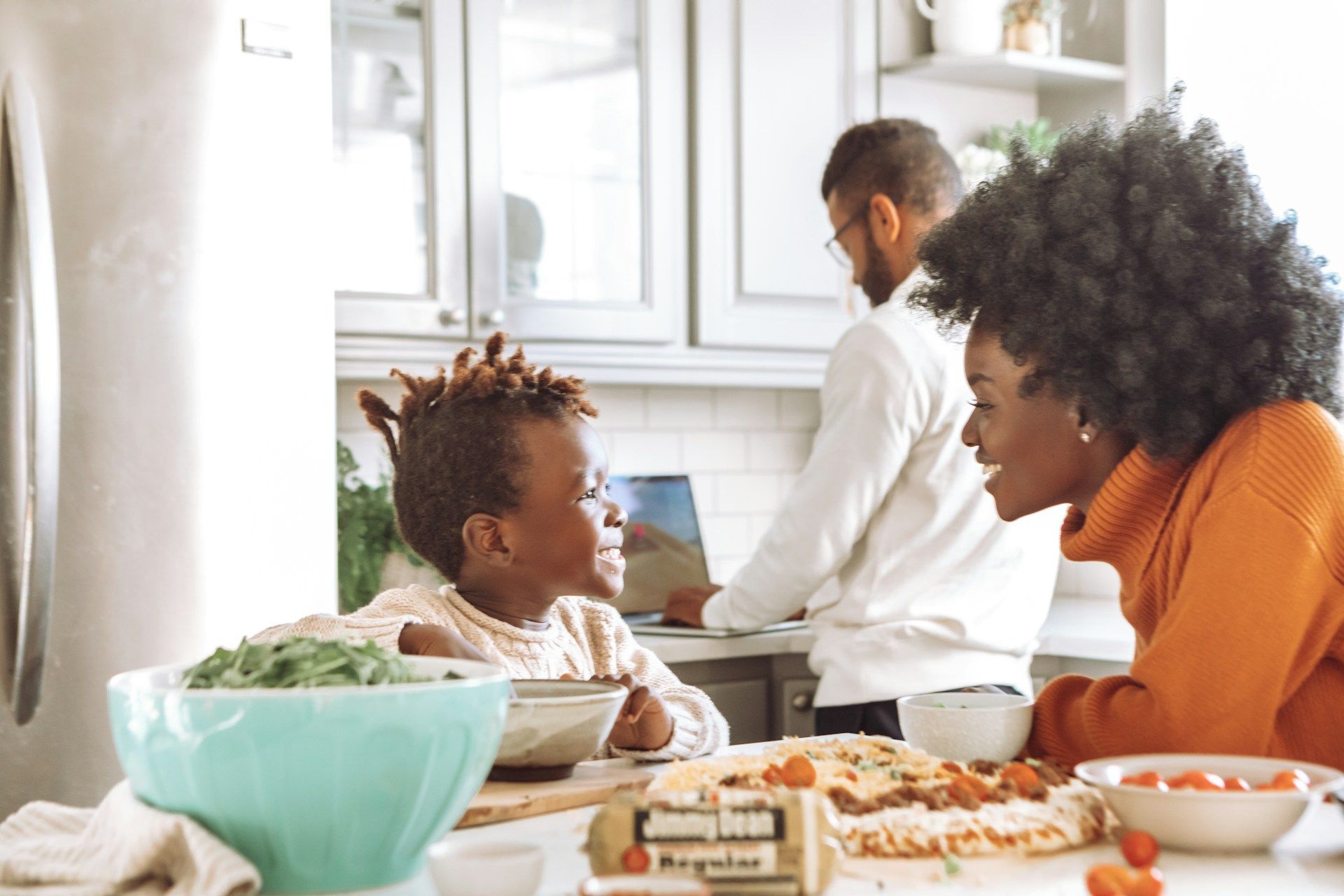 Family cooking together in a bright kitchen, with a child, adult, and food on the counter
