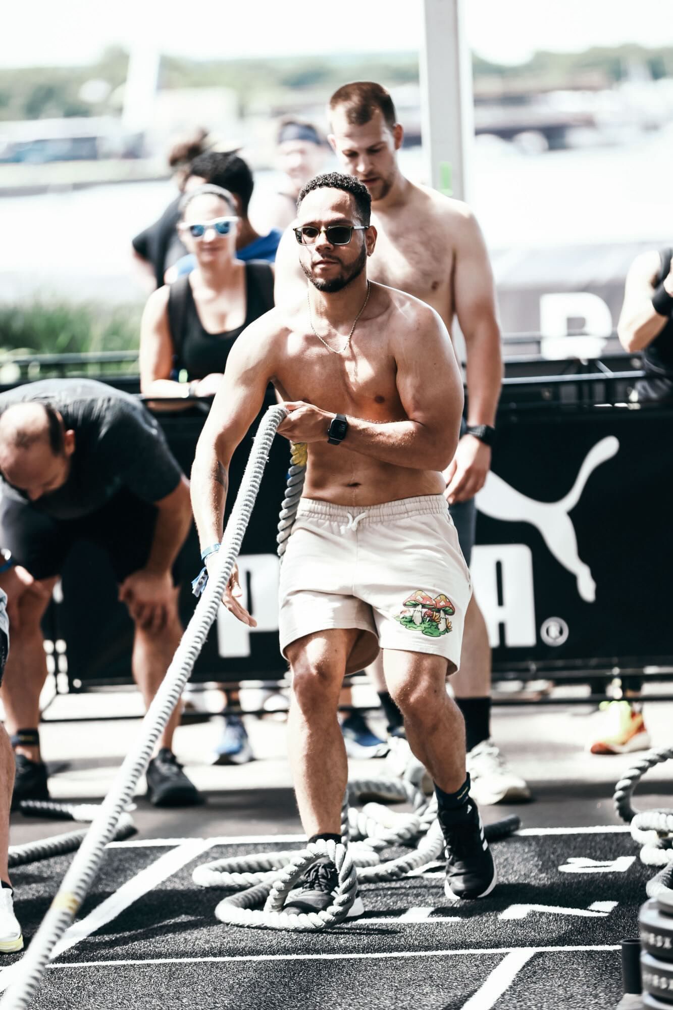 Athlete in sunglasses exercises with battle ropes at an outdoor fitness event