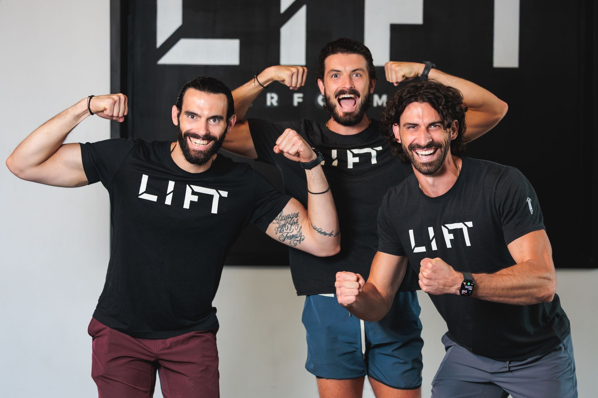 Three men in black shirts with "LIFT" flexing muscles in front of a logo.