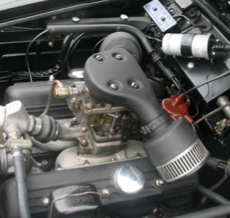 A close up of a car engine with a hose attached to it