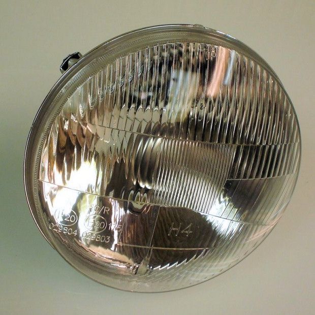 Round car headlight with a ribbed glass lens, H4 designation visible.