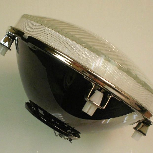Headlight assembly with a chrome ring and clear lens. Black body.