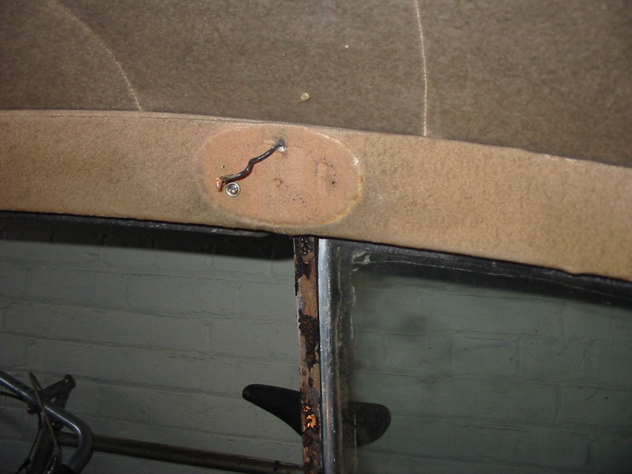 Close-up of a car's headliner with an oval-shaped patch and wire visible near the windshield.