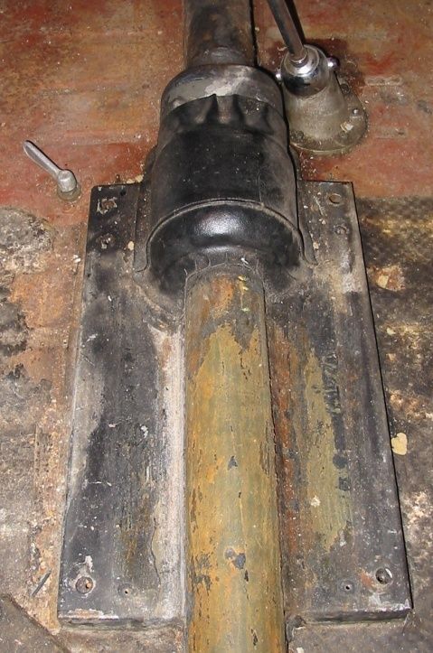 Black machinery base with a rusted metal pipe rising from it. A silver lever sits on the right.
