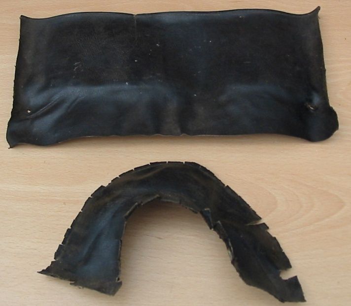 Two pieces of black leather on a light wood surface; one is rectangular, the other curved.