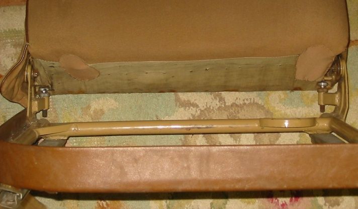 Tan car seat back with metal frame, showing wear.