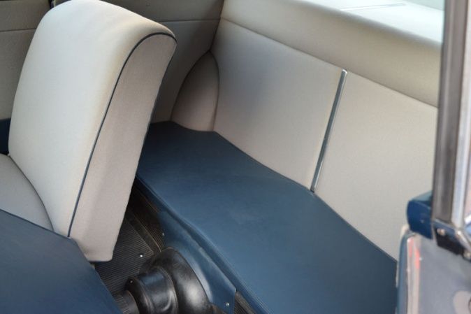 Blue and white vintage car interior with bench seat and backrest.