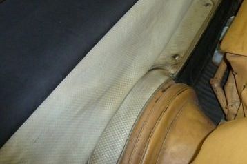 Tan car interior detail showing fabric panel, leather seat, and dark trim.