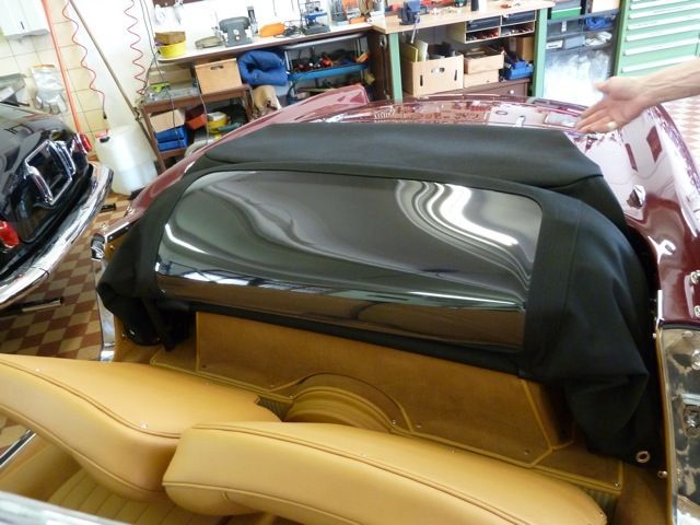 Black convertible top with clear window on a classic car, tan seats.