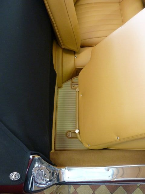 Interior car view of tan leather seats and a black sidewall. Beige floor mat visible.