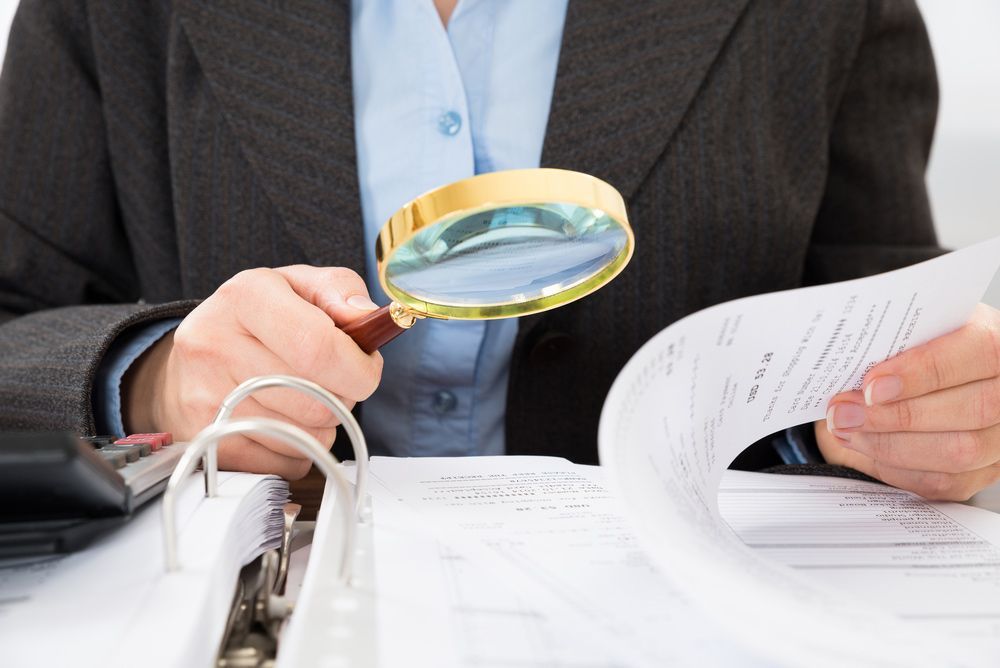 A Woman Is Looking Through A Magnifying Glass At A Piece Of Paper — Surveillance NQ In Aitkenvale, QLD