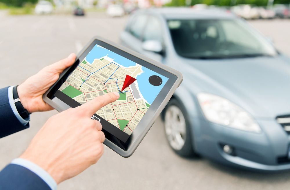A Man Is Holding A Tablet With A Map On It In Front Of A Car — Surveillance NQ In Aitkenvale, QLD