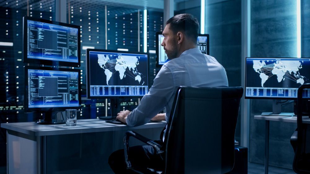 A Man Is Sitting In Front Of A Computer In A Server Room — Surveillance NQ In Mackay, QLD