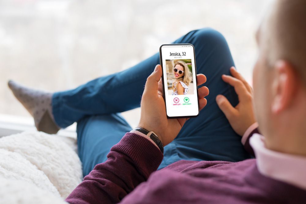 A Man Is Sitting On A Couch Holding A Cell Phone With A Picture Of A Woman On It — Surveillance NQ In Aitkenvale, QLD