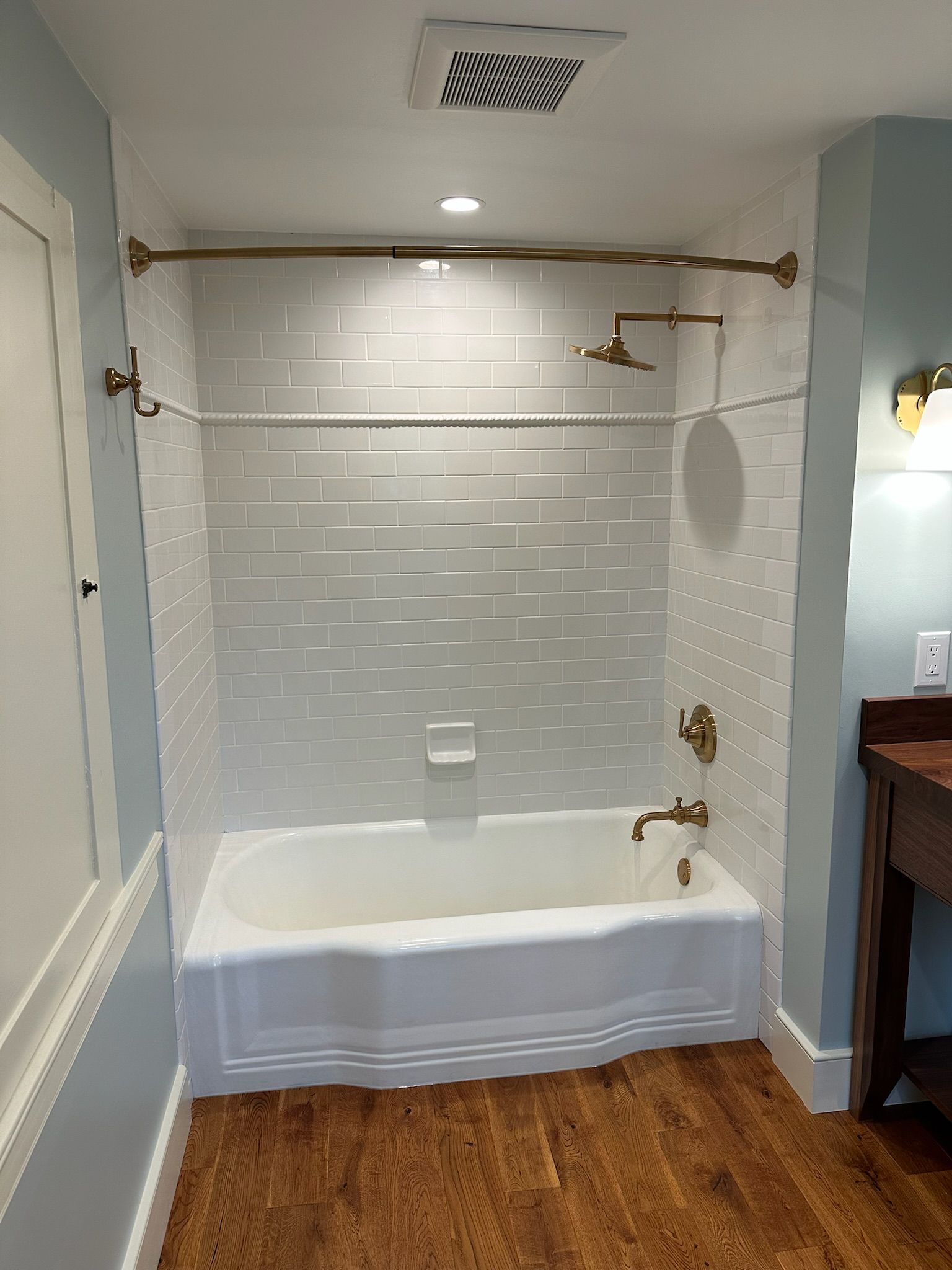 Person installing chrome shower fixture on gray tile wall.