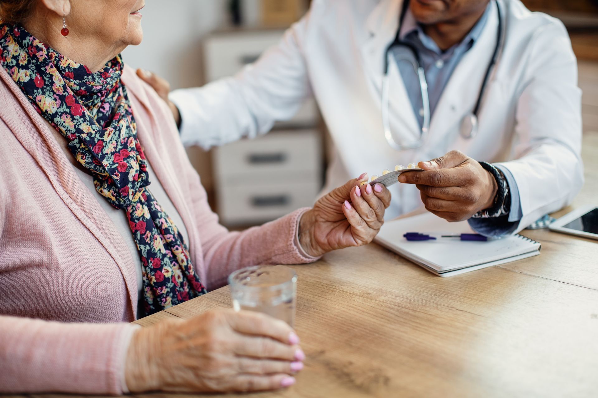 Doctor handing medicine to patient at a table in a clinic
