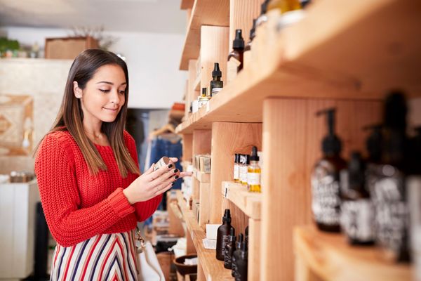 Woman in a red sweater browsing products on wooden shelves in a shop