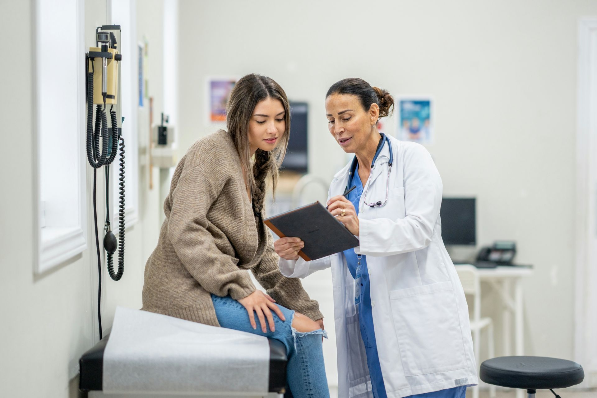 Doctor showing test results to a seated patient in a bright exam room