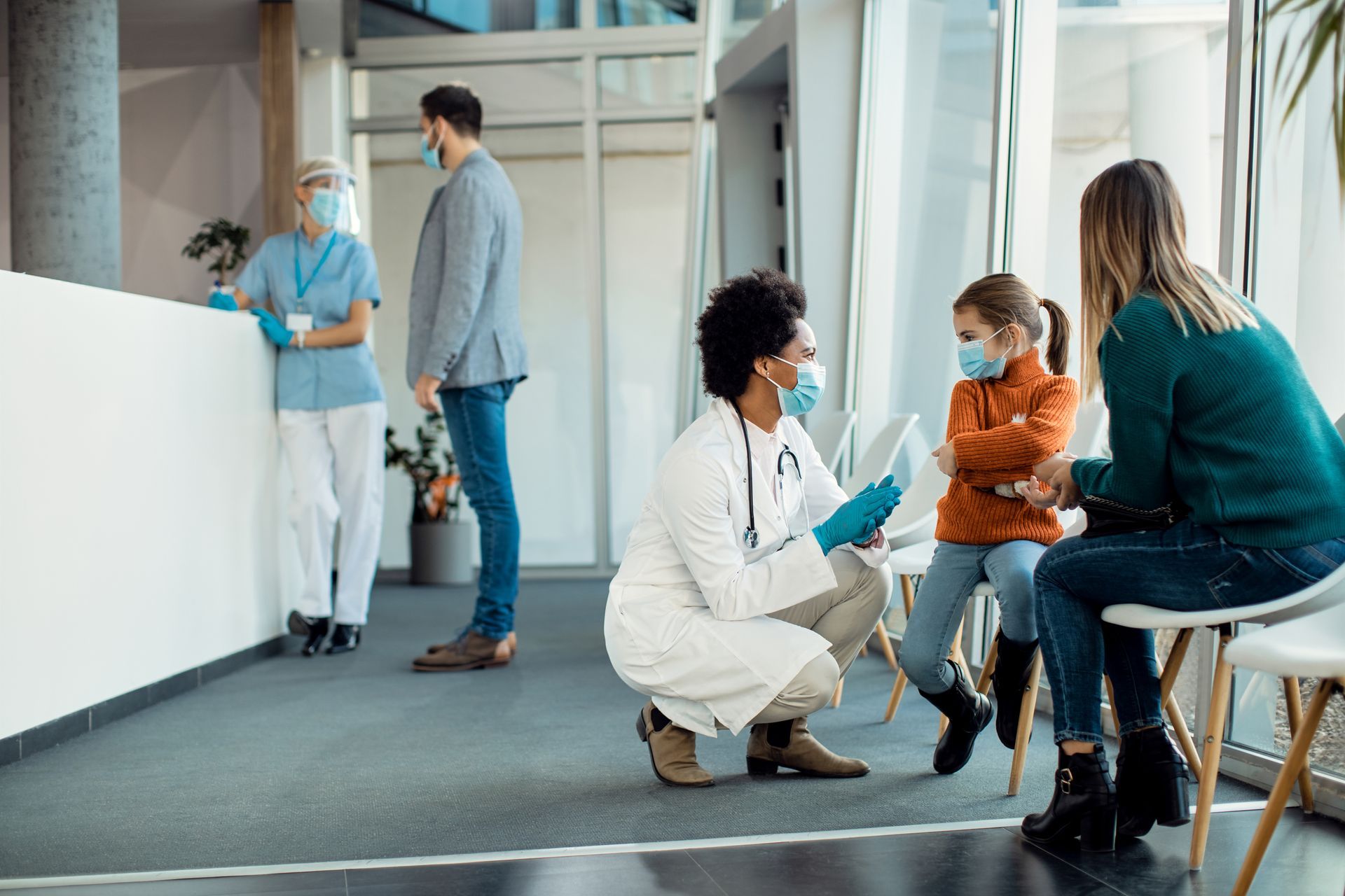 Healthcare workers consulting with seated patients in a bright clinic waiting area