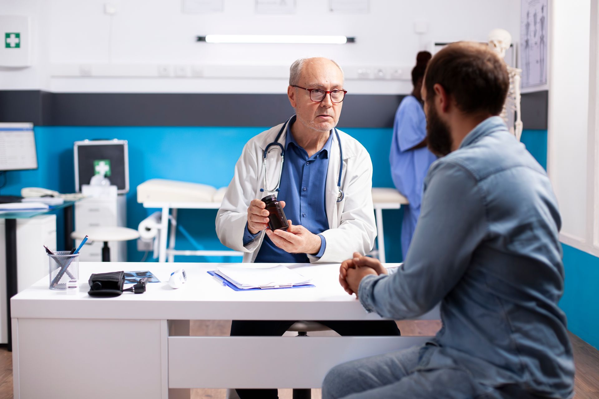 Doctor talking with a patient in a bright clinic office, seated across a desk with papers and a stethoscope.