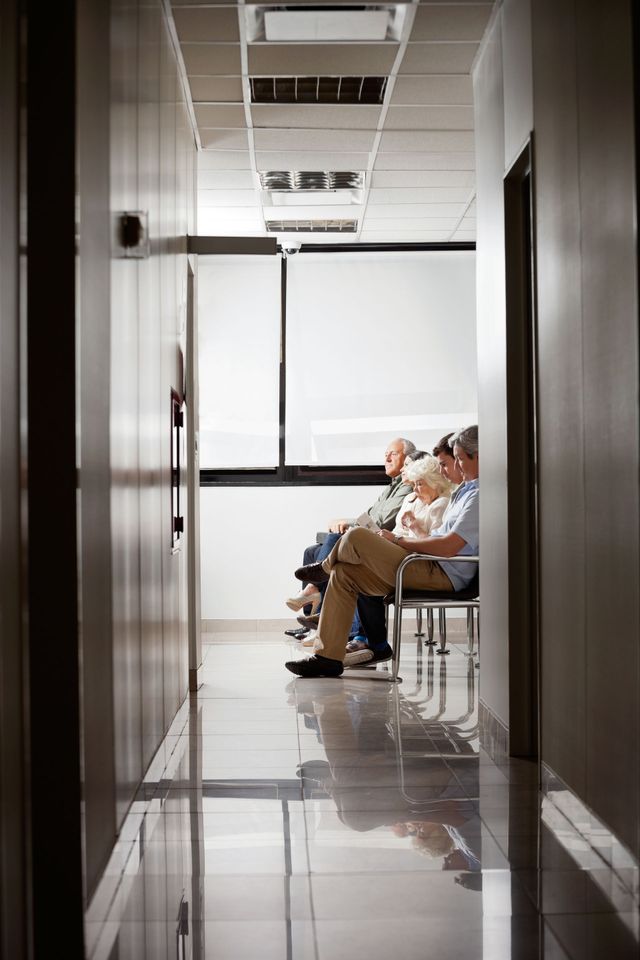 People sitting on chairs in a bright hallway with a reflective floor