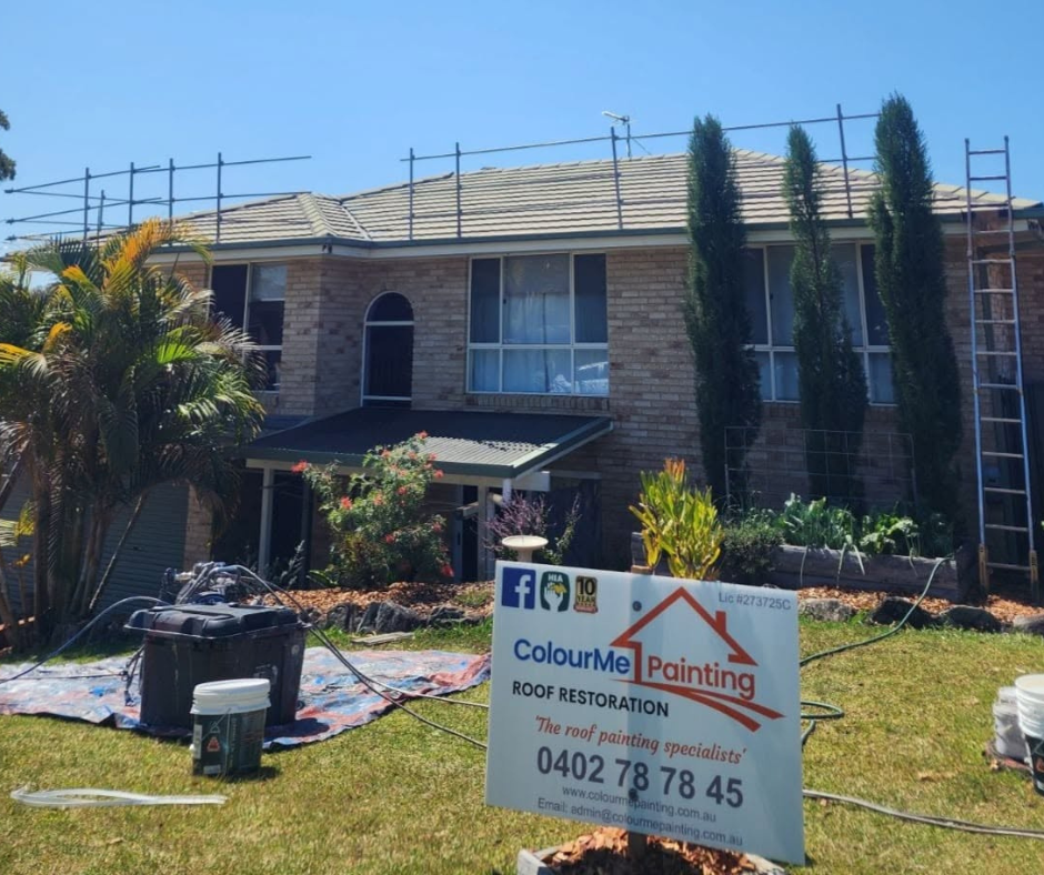 House exterior with roof scaffolding and a painting contractor sign in the front yard