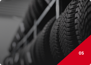 Black-and-white close-up of stacked tires with a red corner label reading “05” | Frisco Automotive & Transmission