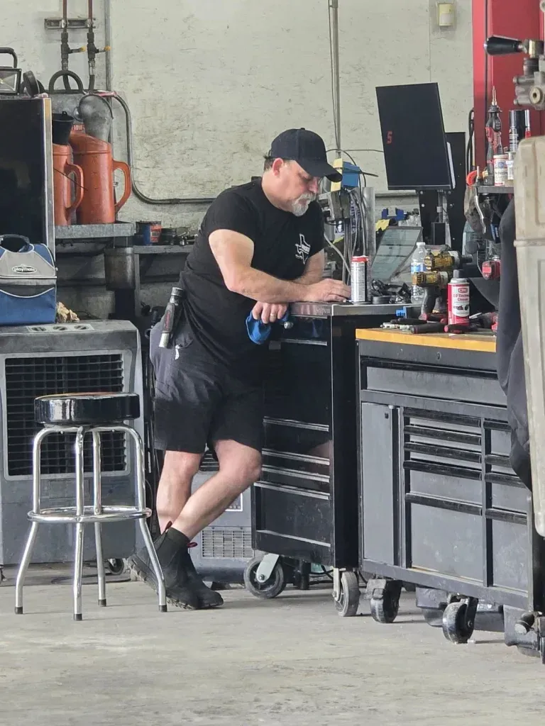 Mechanic in black leaning on tool chest in a garage workshop | Frisco Automotive & Transmission