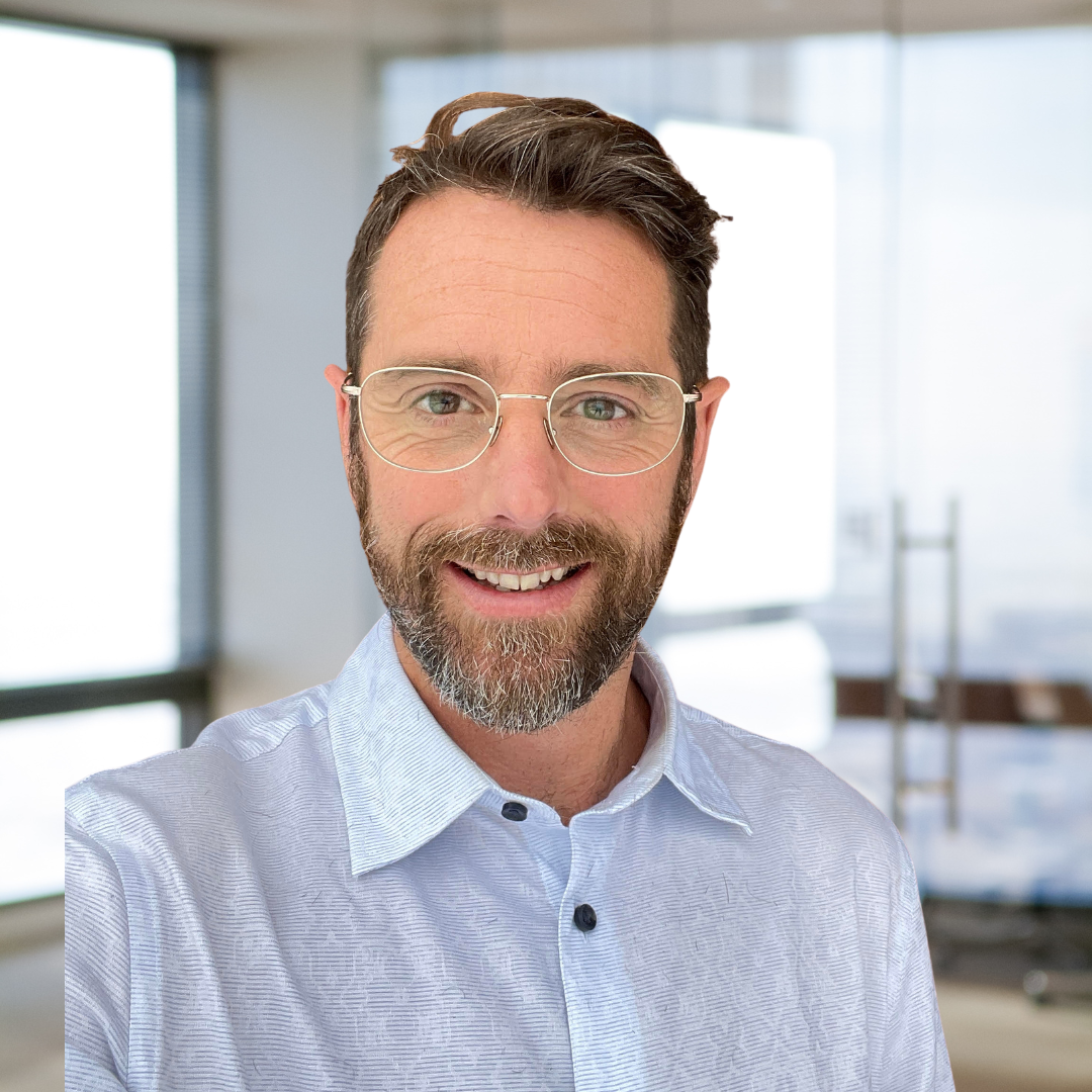 A man with a beard and glasses is smiling for the camera.