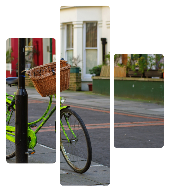 Green bicycle with wicker basket parked beside a street and building facade