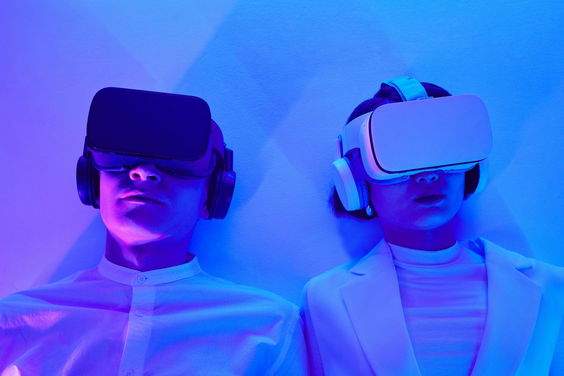Two people in VR headsets lit by blue and purple neon light