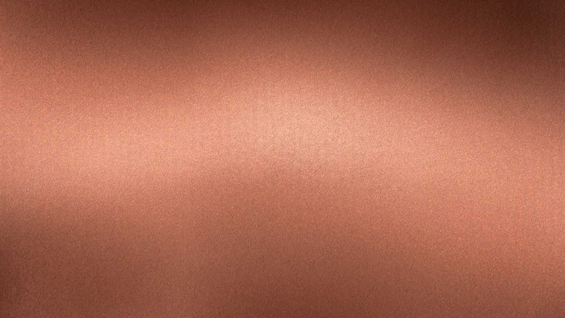 A close up of a copper metal texture with a shadow on it.