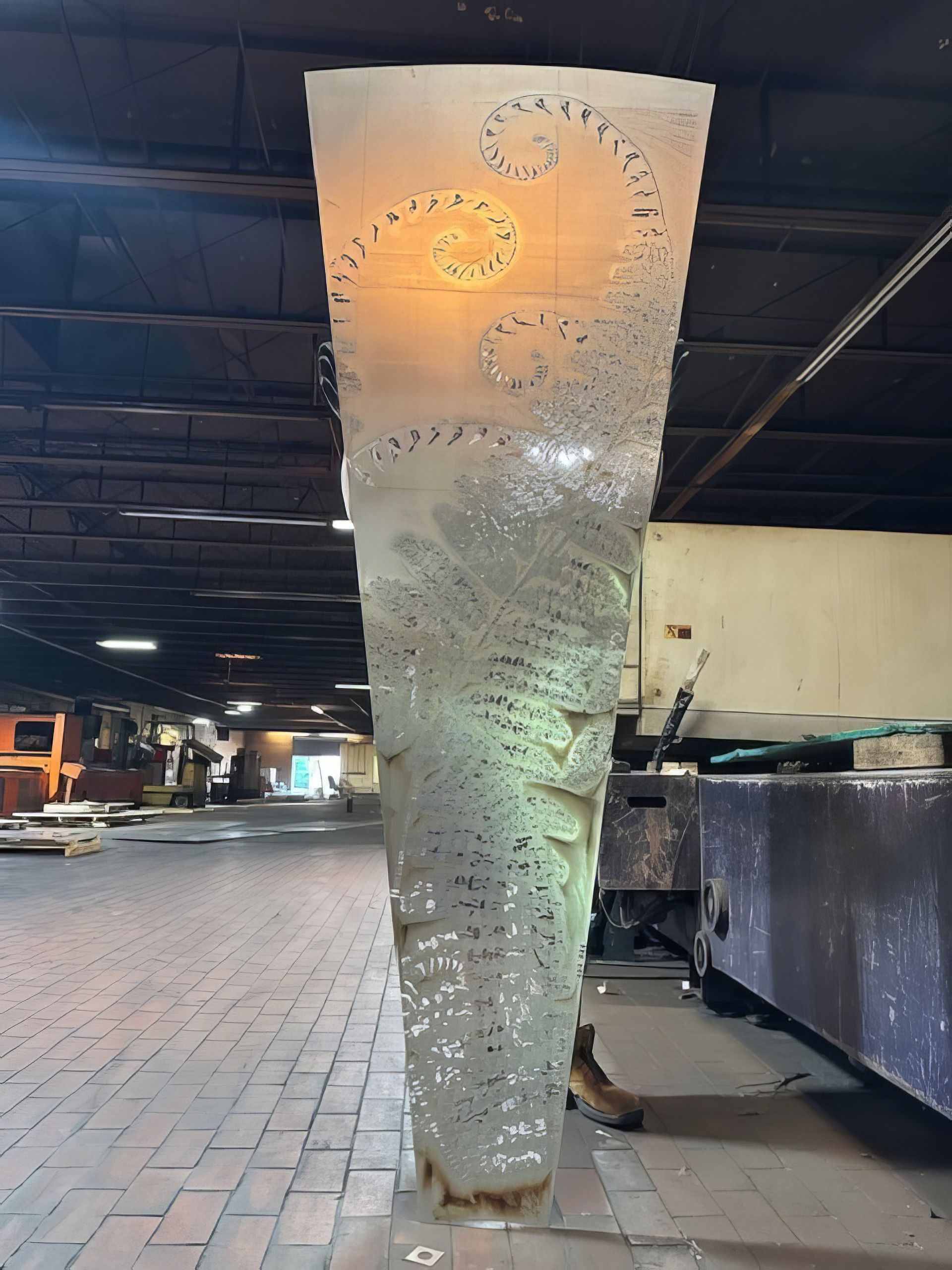 A large sculpture is sitting on a brick floor in a warehouse