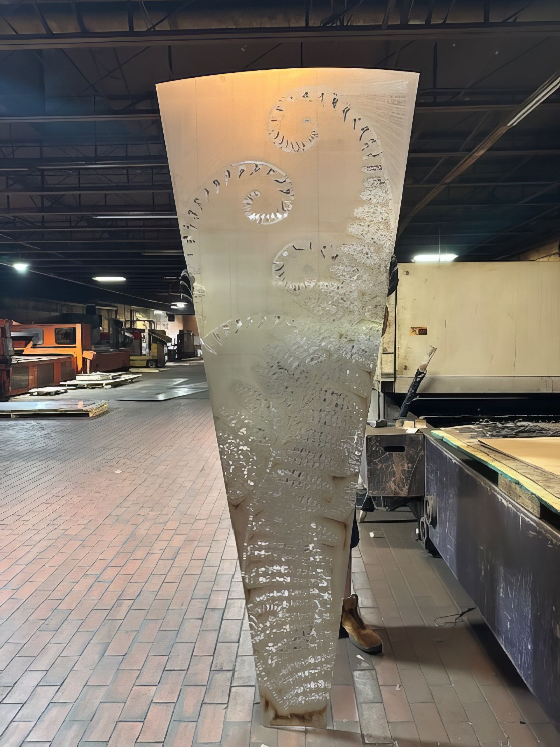 A large cone shaped object is sitting on a brick floor in a warehouse