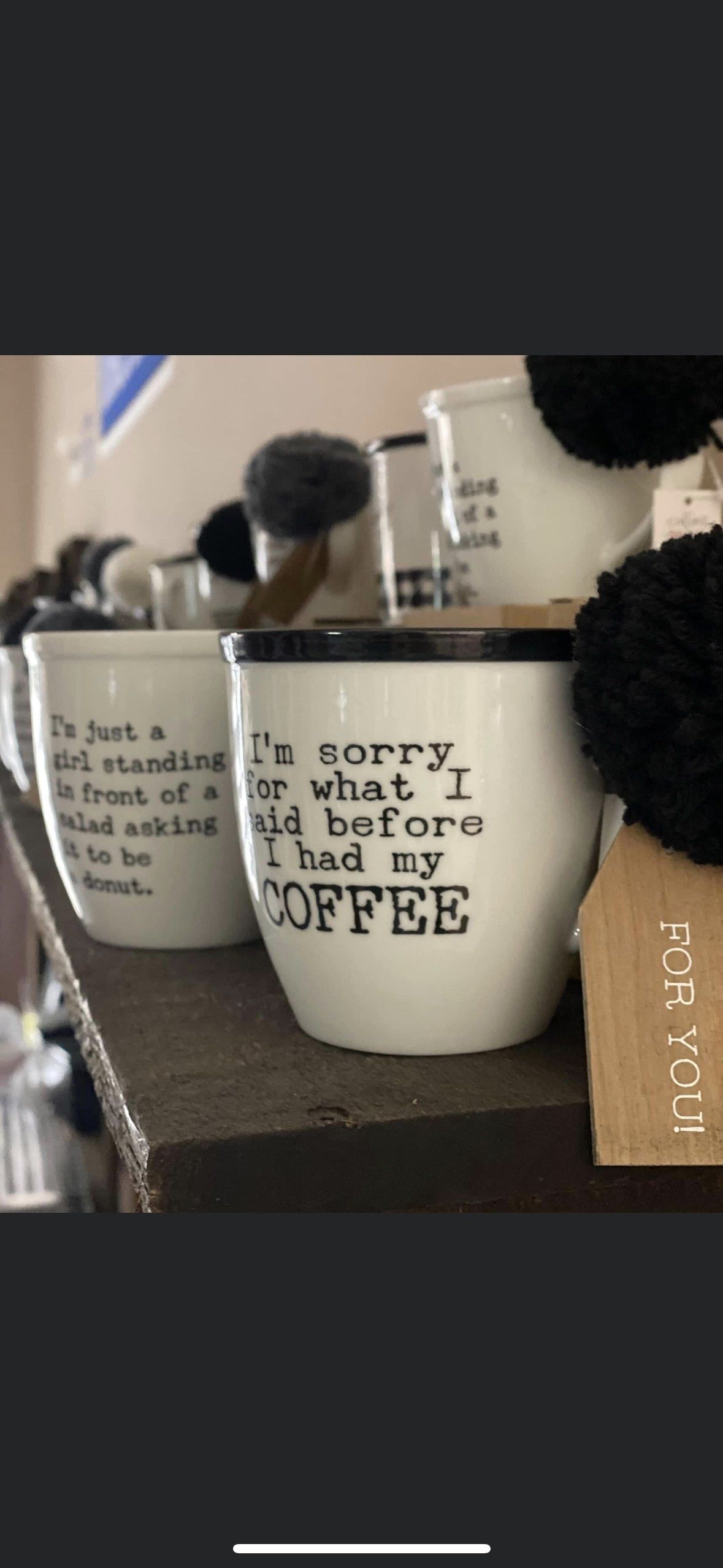 A row of white mugs with text, including