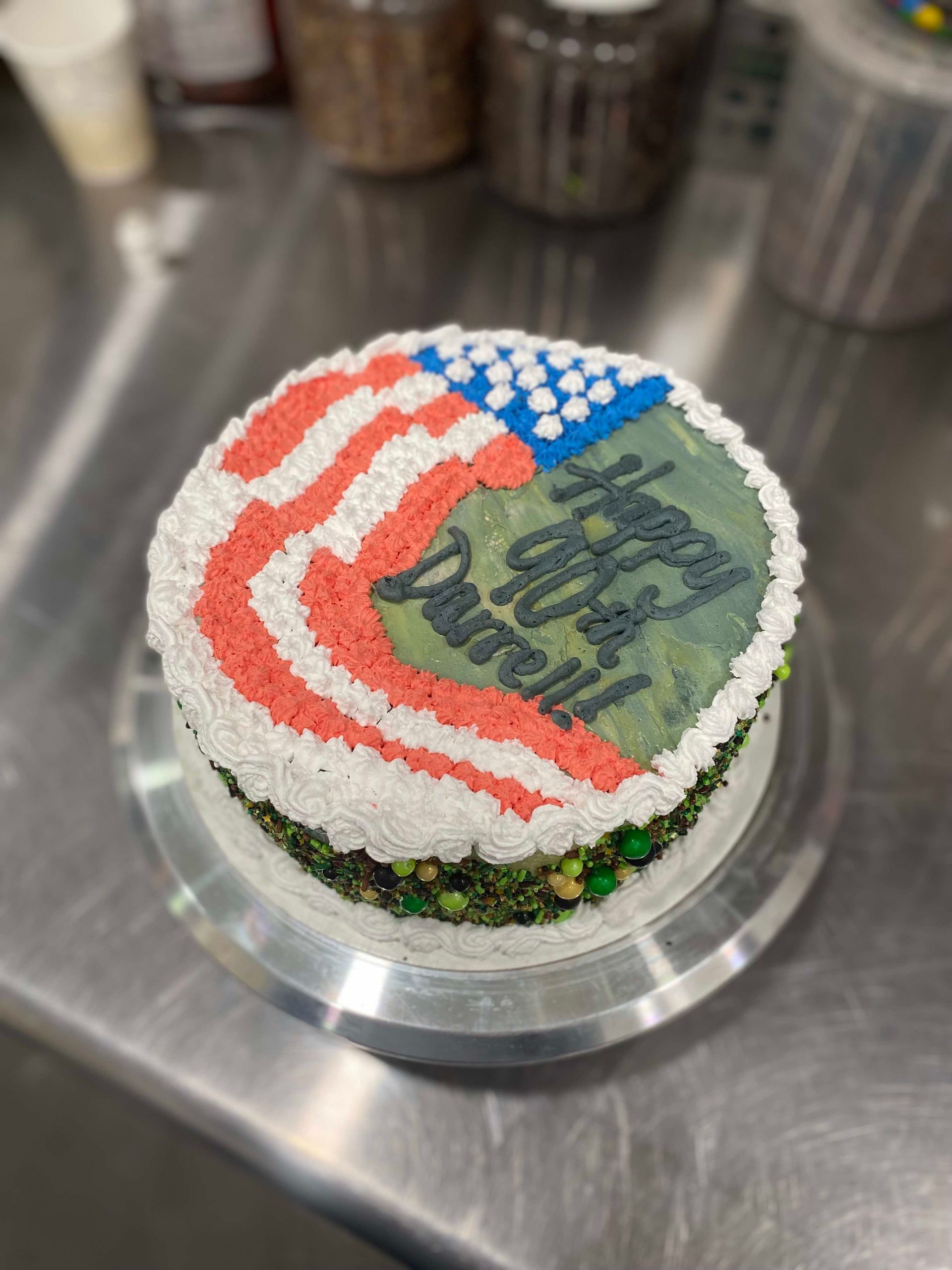 A round cake decorated with a US flag design and text reading