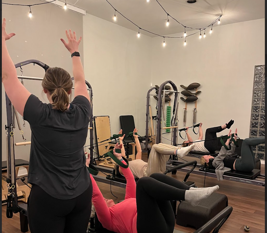 pilates instructor with students on reformer apparatus