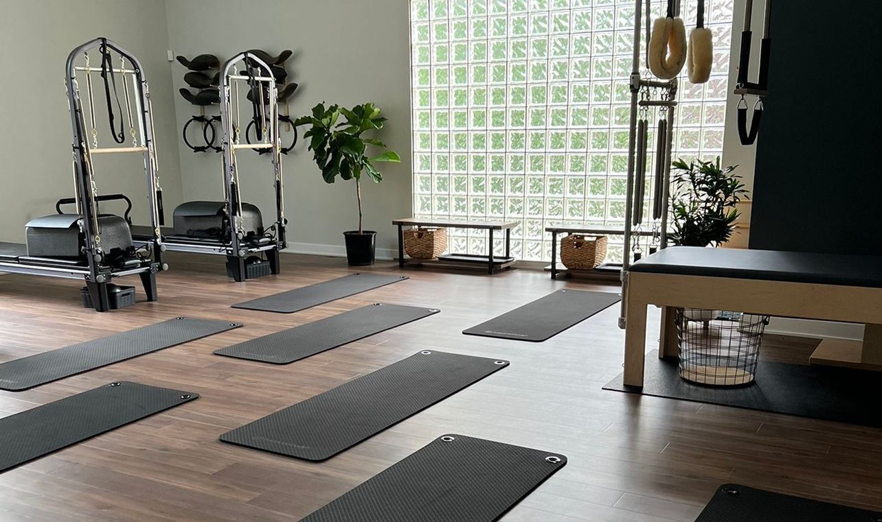 Clients are doing pilates on reformers in a large room.