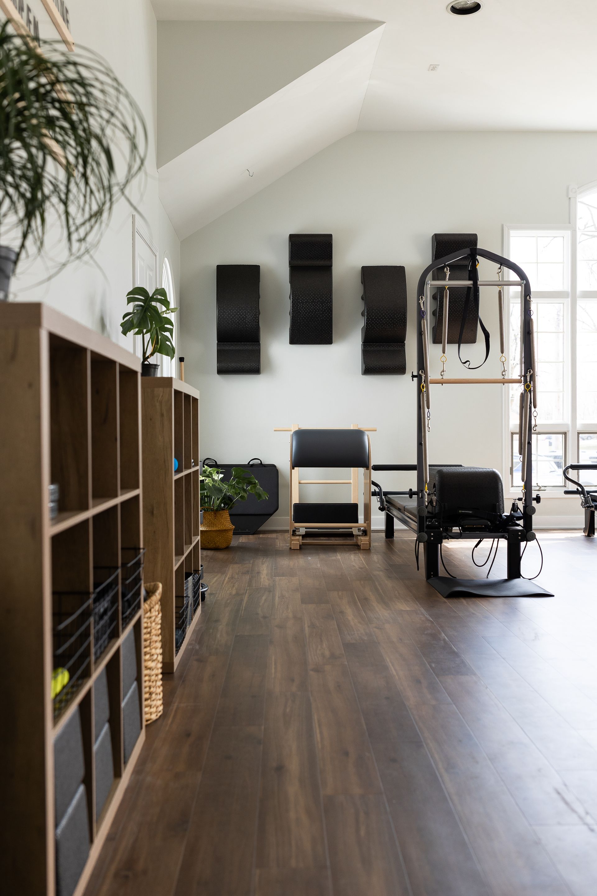 A view of a pilates studio with elegant storage cubbies, a reformer, and additional equipment on the wall.
