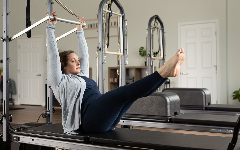 woman utilizing the tower bar on a pilates reformer