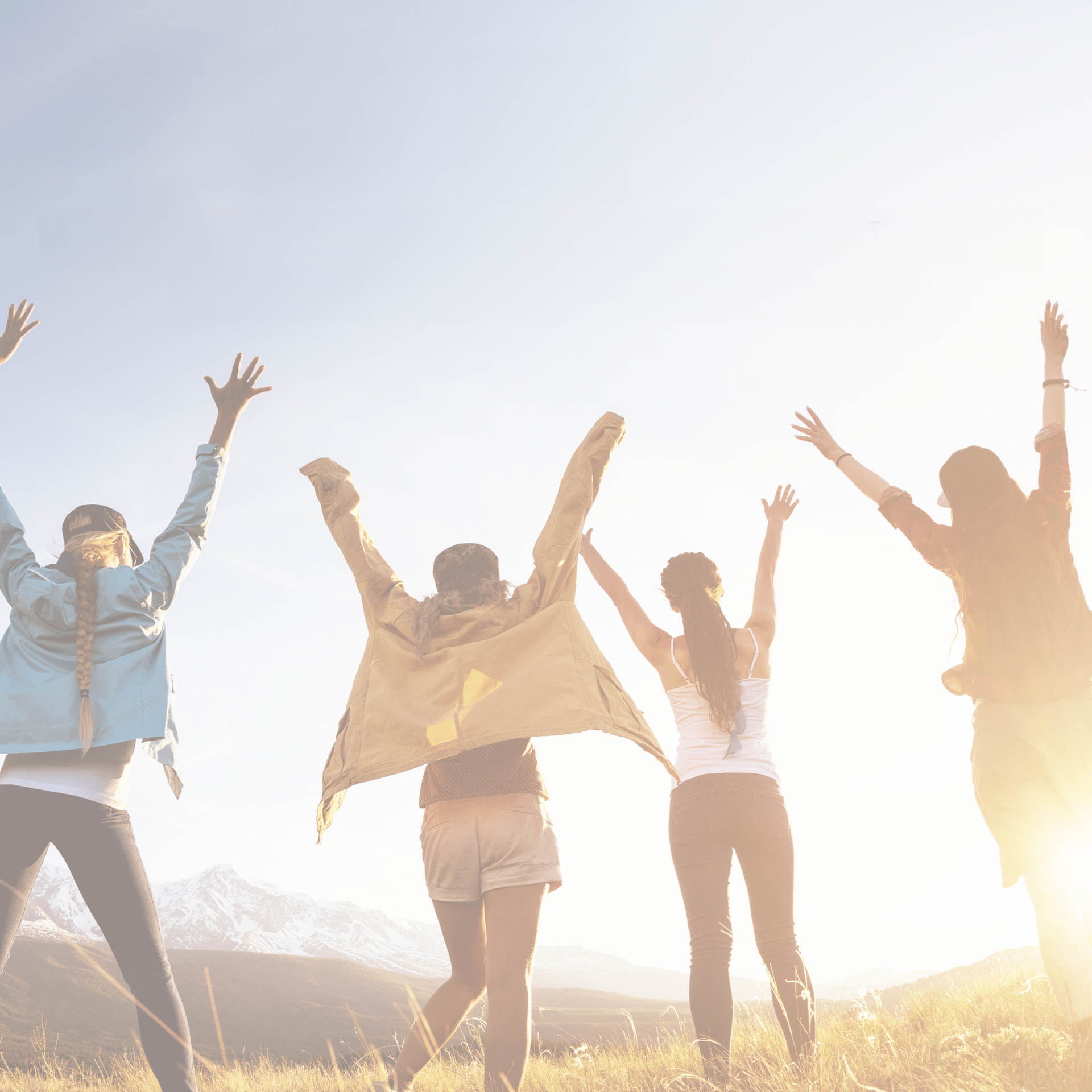 A group of people are standing in a field with their arms in the air.