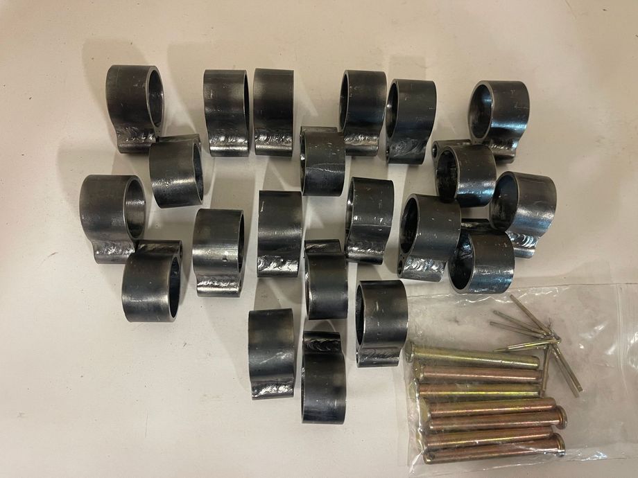 7 sets of 3 hinges and pins arranged with a small plastic bag of metal pins on a plain white surface.
