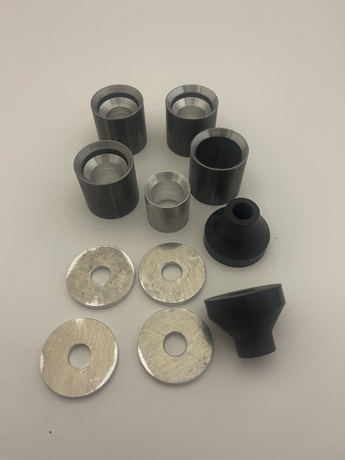 A set of metal and aluminum bushings and 8 black rubber mounts arrranged on a plain white surface.