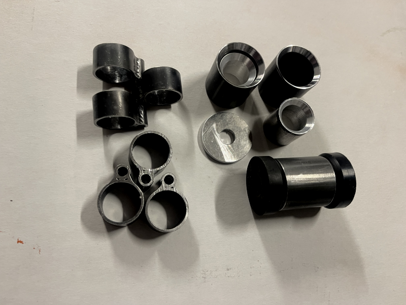Assorted metal machine components, including hinges, station #1 engine mounts, rubber bushings and aluminum washers.